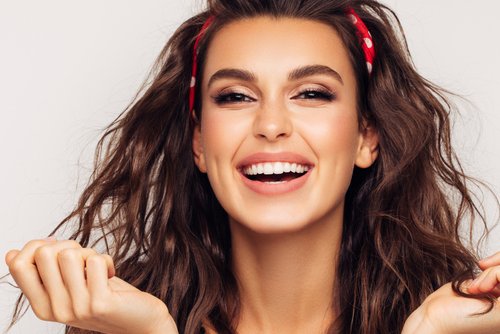 A brunette woman wearing a hairband with a bright smile