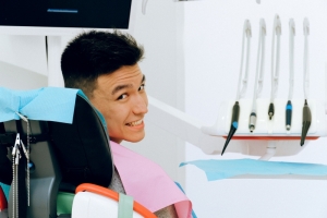 patient in dental operating chair looking back and smiling , with an array of dental tools next to him