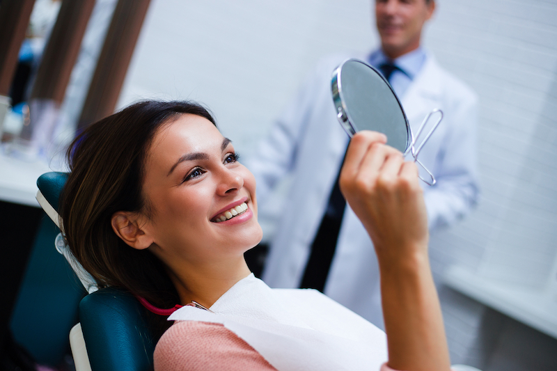 Female dental patient looking at her teeth in a mirror