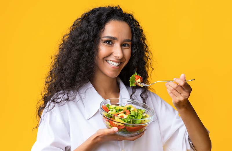Woman eating a salad and smiling 