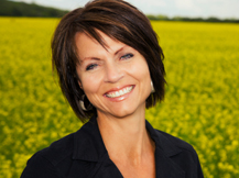 Woman smiling in a field | Endodontic Treatment in Calgary