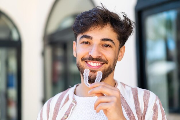 handsome-arab-man-outdoors-holding-invisible-braces-with-happy-expression