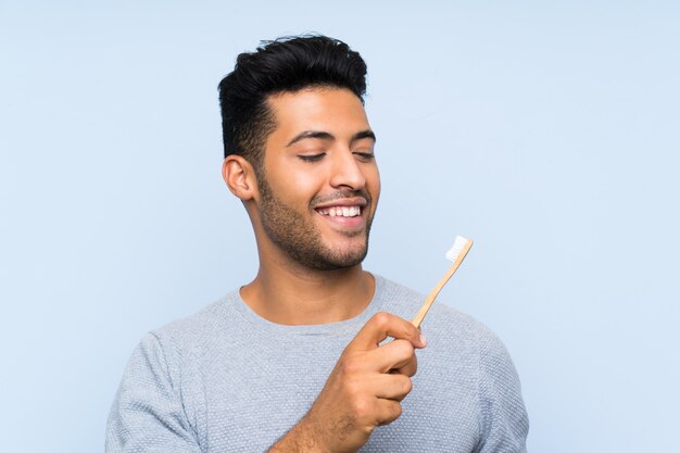young-man-shaving-his-beard-isolated-blue-wall